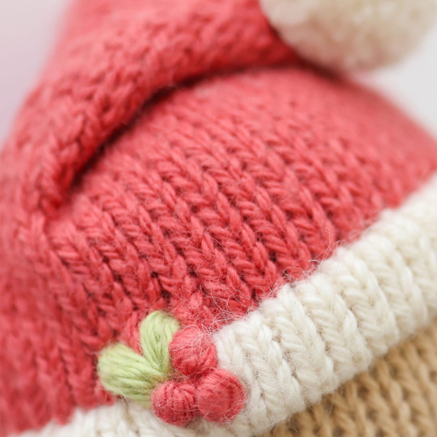 Close-up of a knit red Santa hat with a holly detail