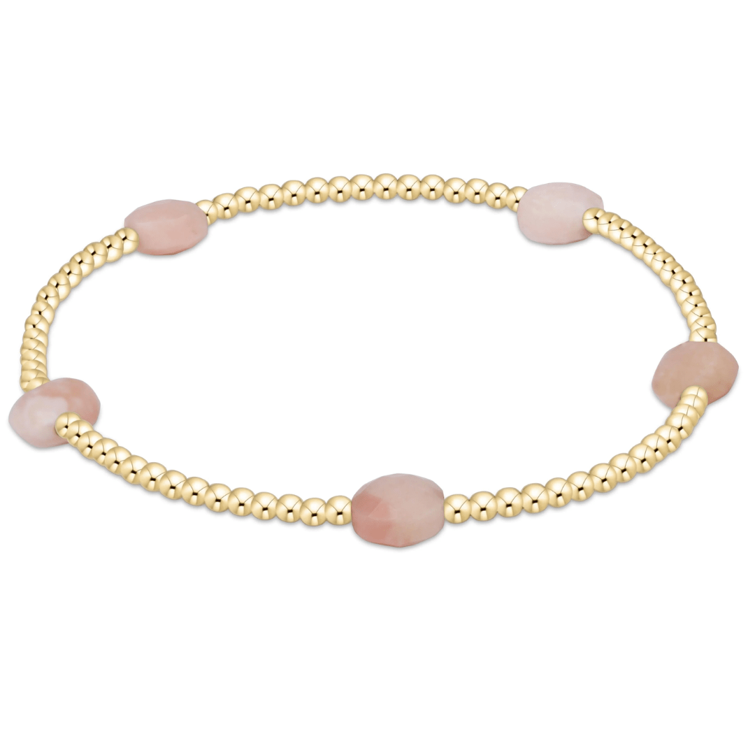 Gold bracelet with pink beads on a white background