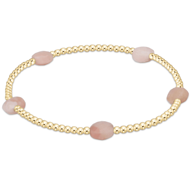 Gold bracelet with pink beads on a white background