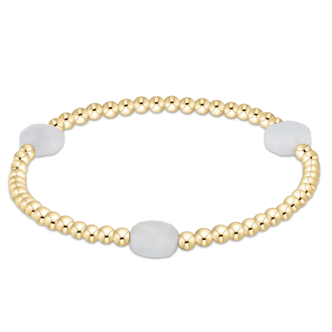 Gold beaded bracelet with white beads on a white background