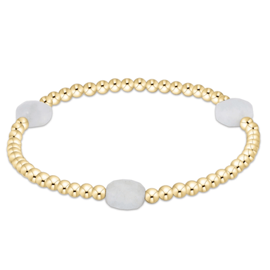 Gold beaded bracelet with white beads on a white background