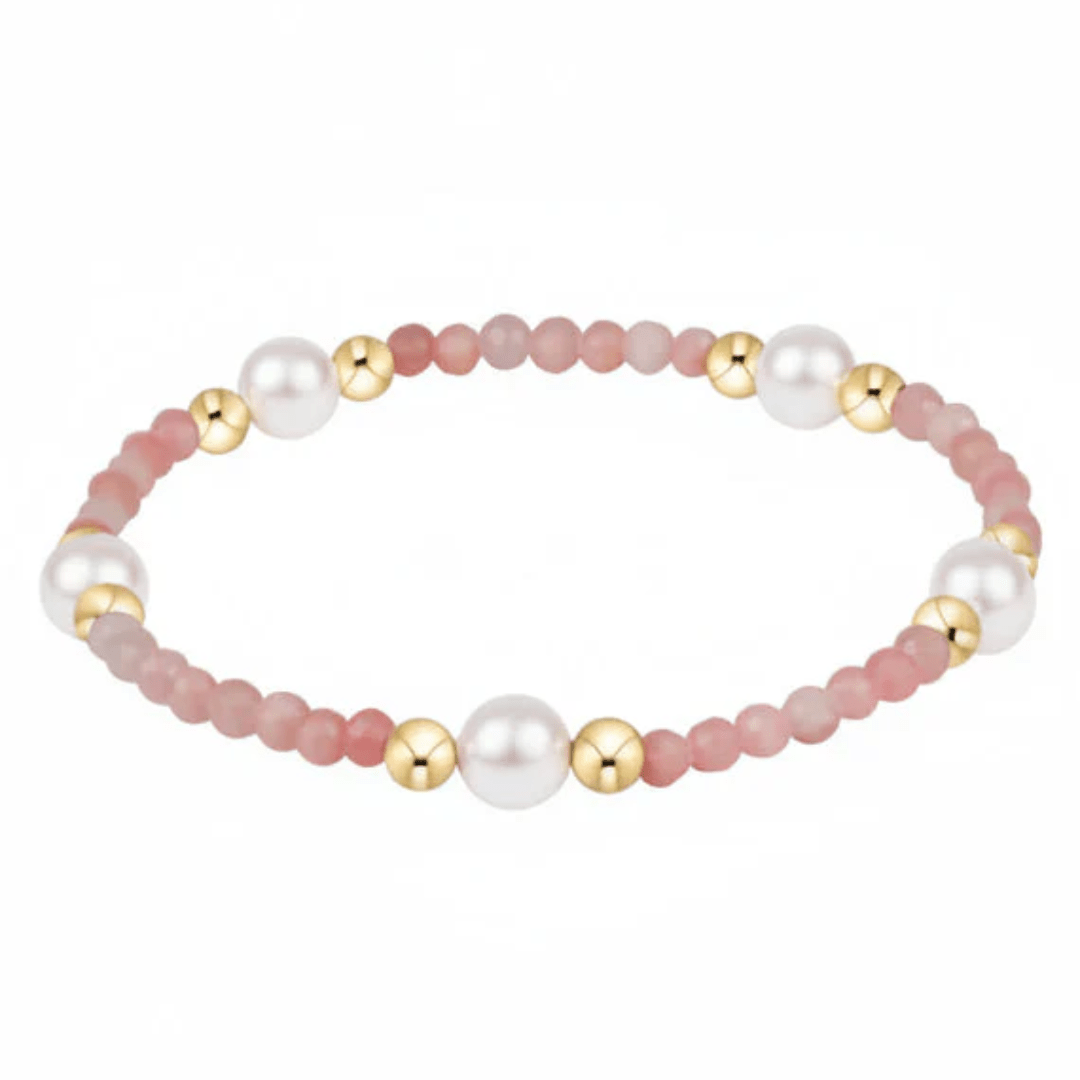 Bracelet with pink beads, gold accents, and pearls on a white background