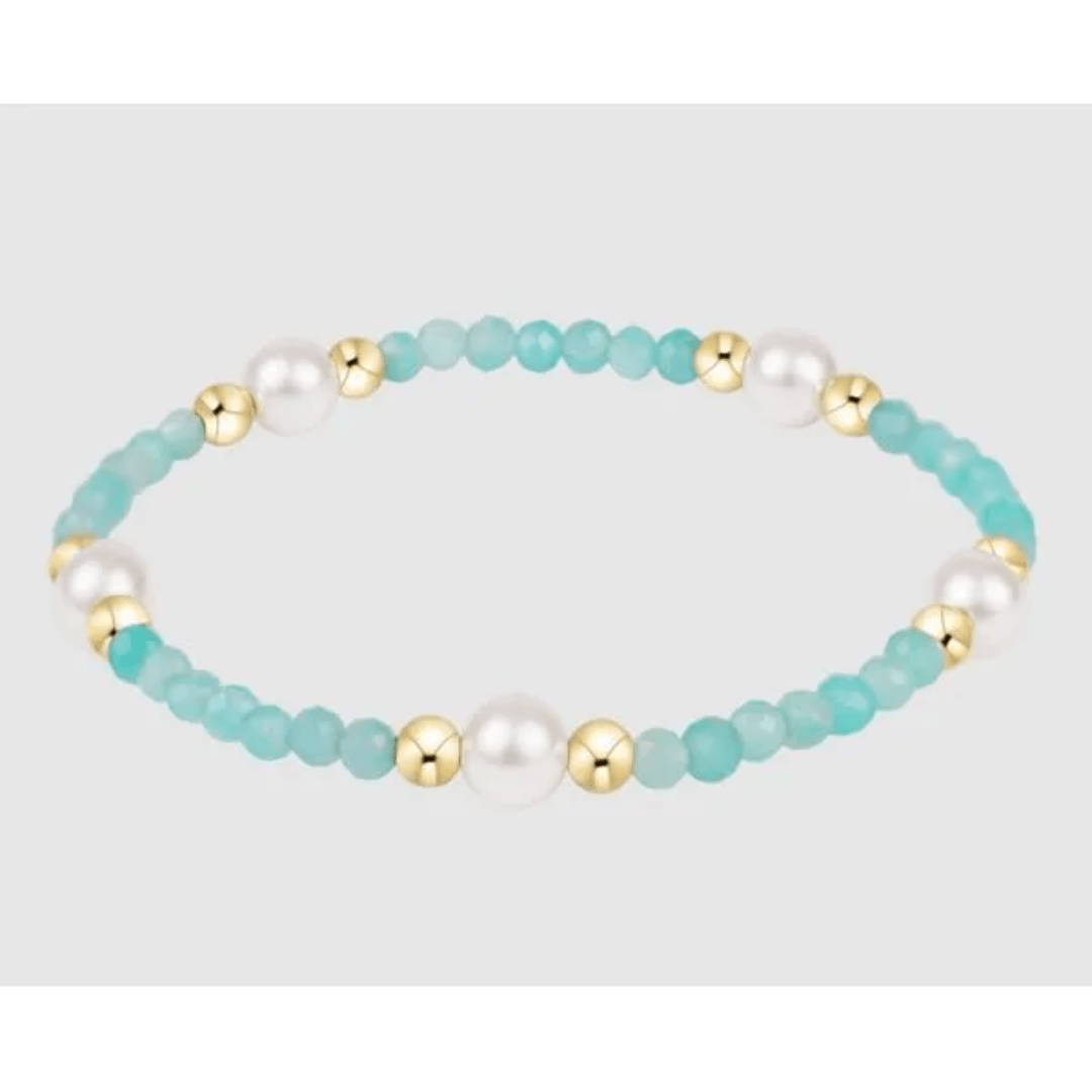 Bracelet with turquoise beads, gold accents, and pearls on a light gray background
