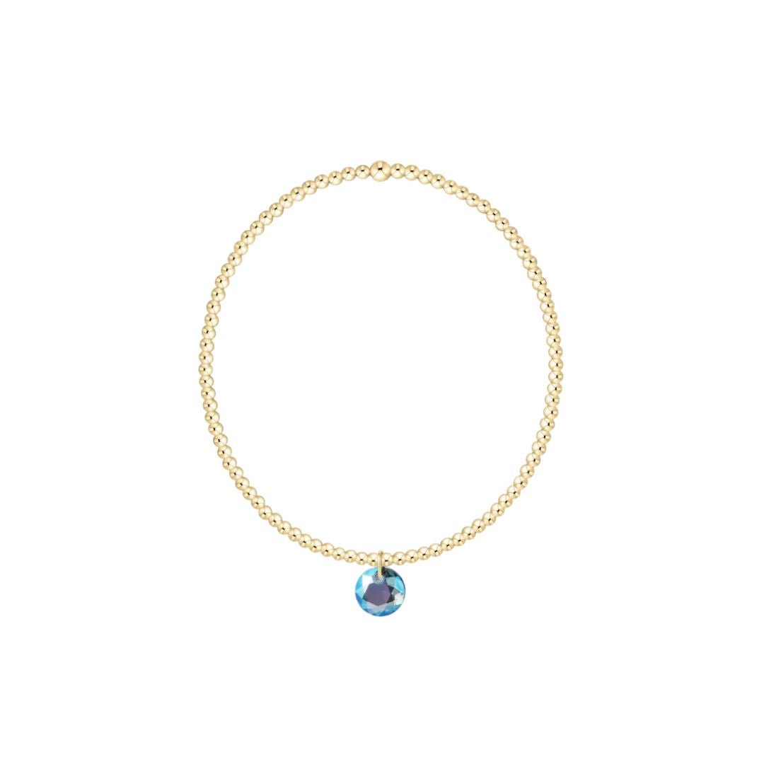 Gold bracelet with a blue gemstone pendant on a white background