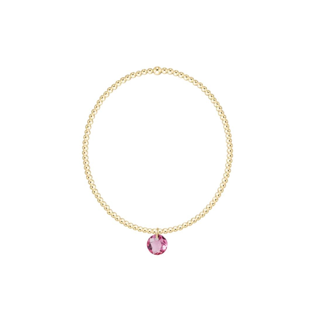 Gold bracelet with a pink gemstone on a white background