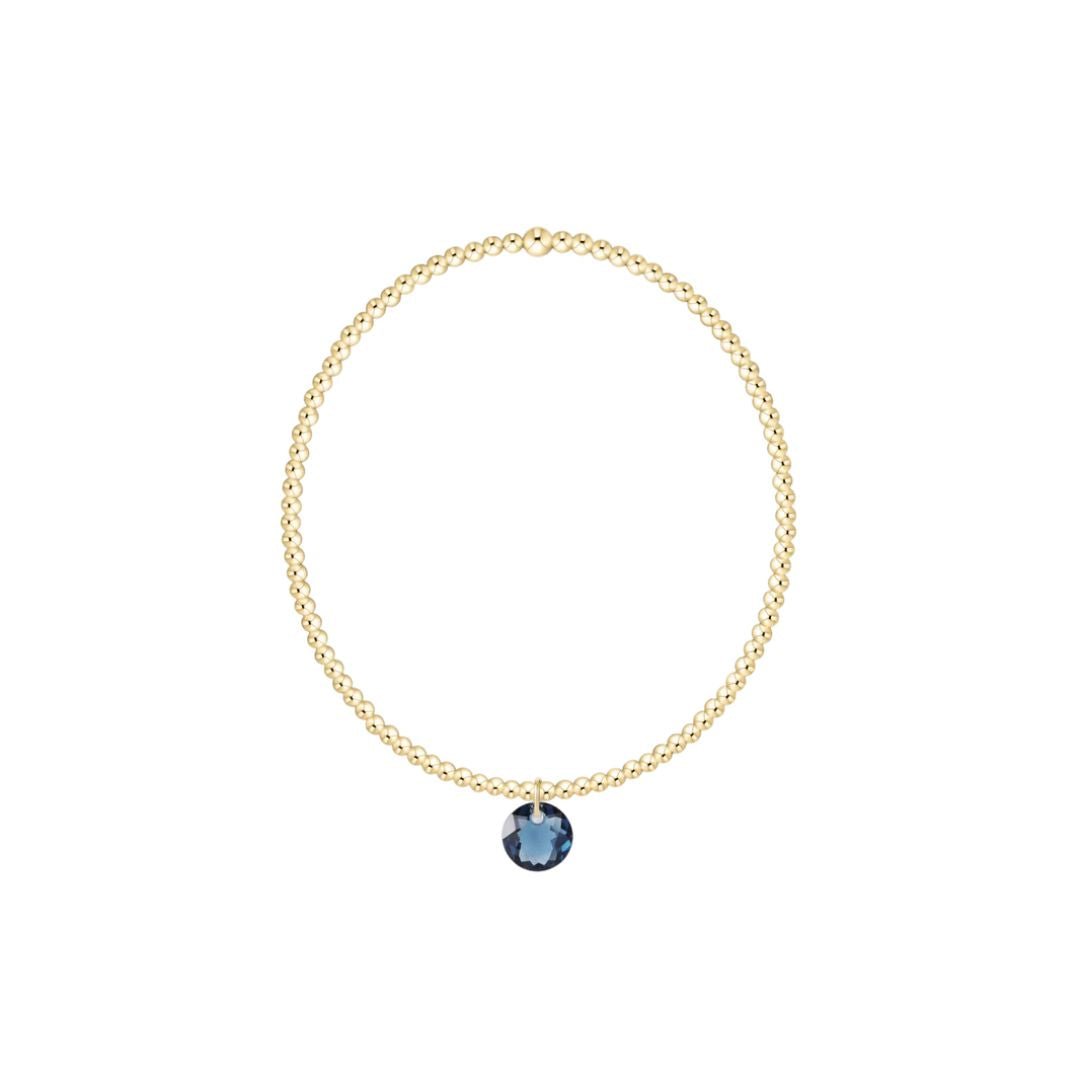Gold bracelet with a blue gemstone pendant on a white background
