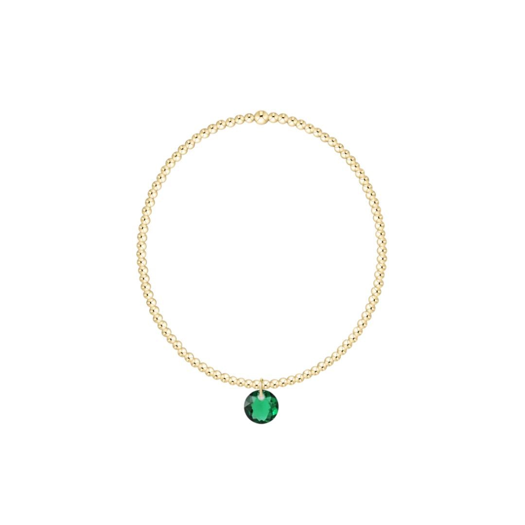 Gold bracelet with a green gemstone on a white background