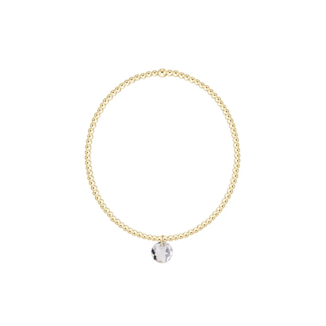 Gold bracelet with a clear pendant on a white background