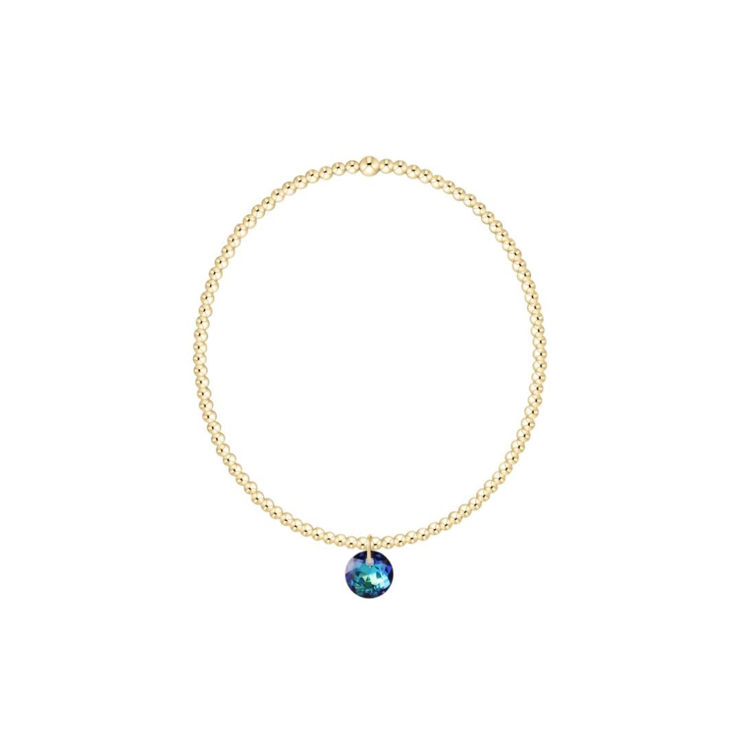 Gold bracelet with a blue gemstone pendant on a white background