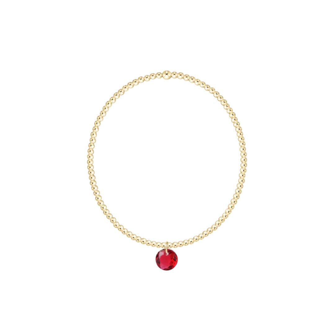Gold bracelet with a red gemstone on a white background