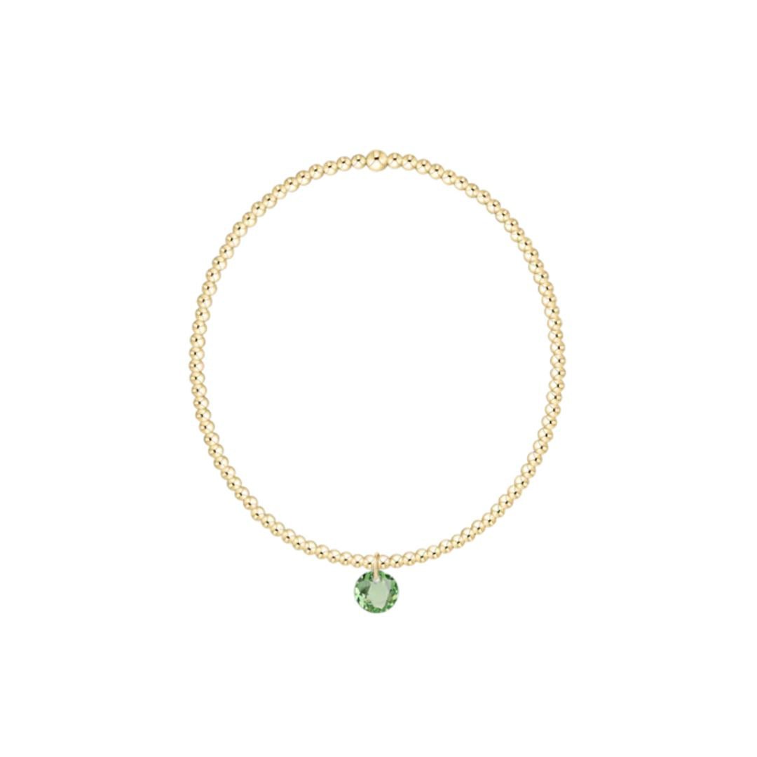 Gold bracelet with a green gemstone on a white background