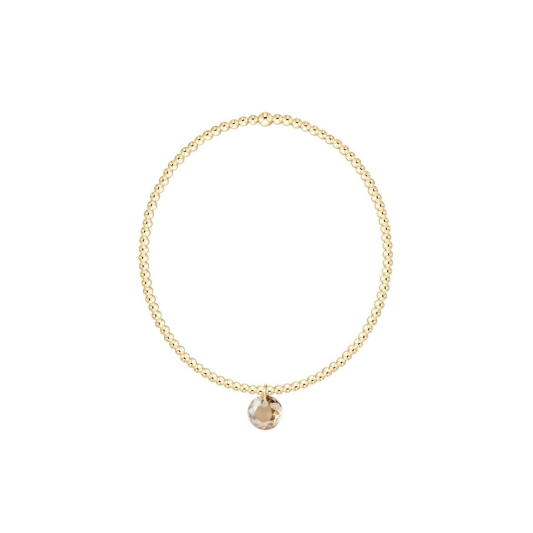 Gold bracelet with a small round pendant on a white background