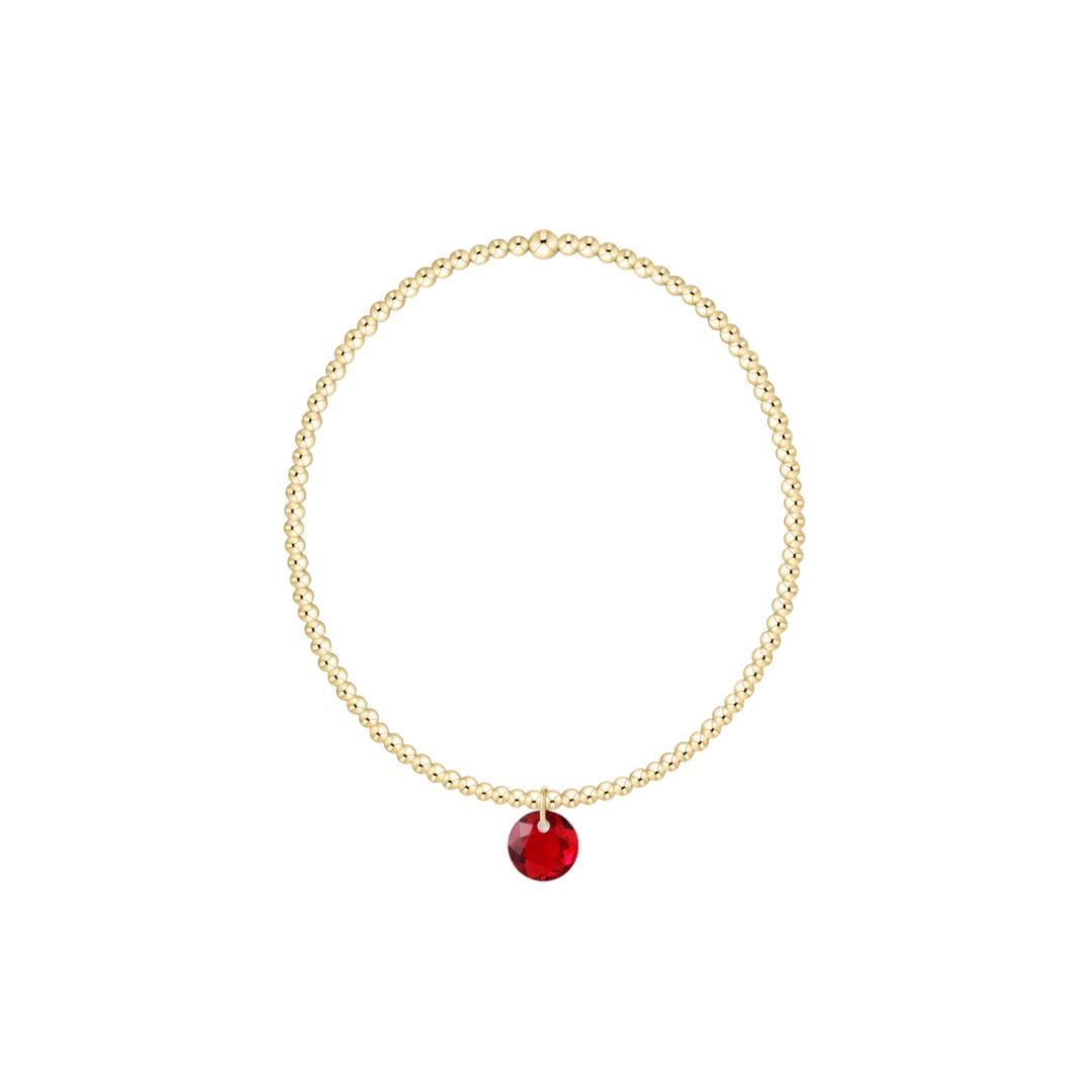 Gold bracelet with a red pendant on a white background