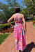 Woman in a colorful dress walking on a brick path with trees and greenery in the background