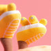 Yellow baby socks with toe separation on a pink background