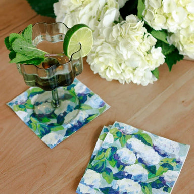 Minty cocktail with lime wedge on floral coasters with white flowers in the background