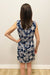 Woman wearing a navy and white patterned dress against a plain wall.