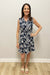 Woman wearing a navy floral dress against a plain wall.
