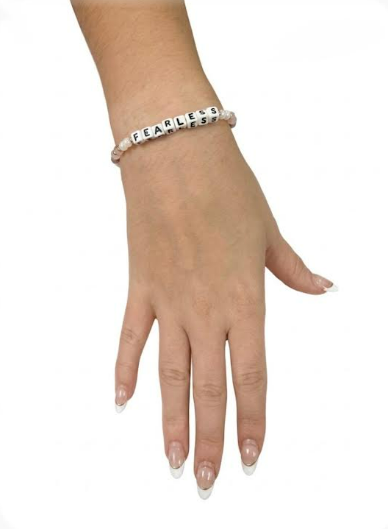 Model wearing the Little Words Project Fearless bracelet in peach and blush crystals
