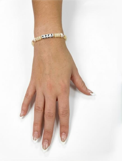Model wearing the Little Words Project Hope bracelet in cream beads