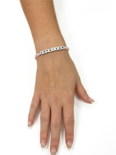 Model wearing the Little Words Project Survivor bracelet in pink beads