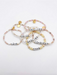 Six Little Words Project word bracelets in pearl, pink, peach, clear and cream beads on a white background