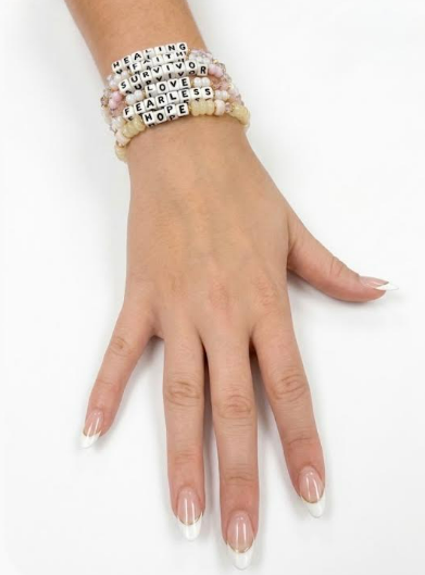 Model wearing a stack of six Little Words Project word bracelets