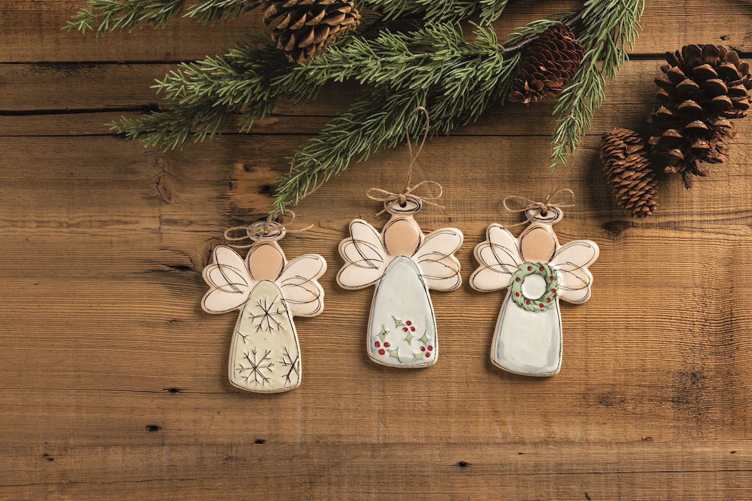 Three angel ornaments on a wood background