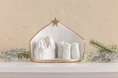 Gold edge Nativity scene displayed on a shelf with greenery