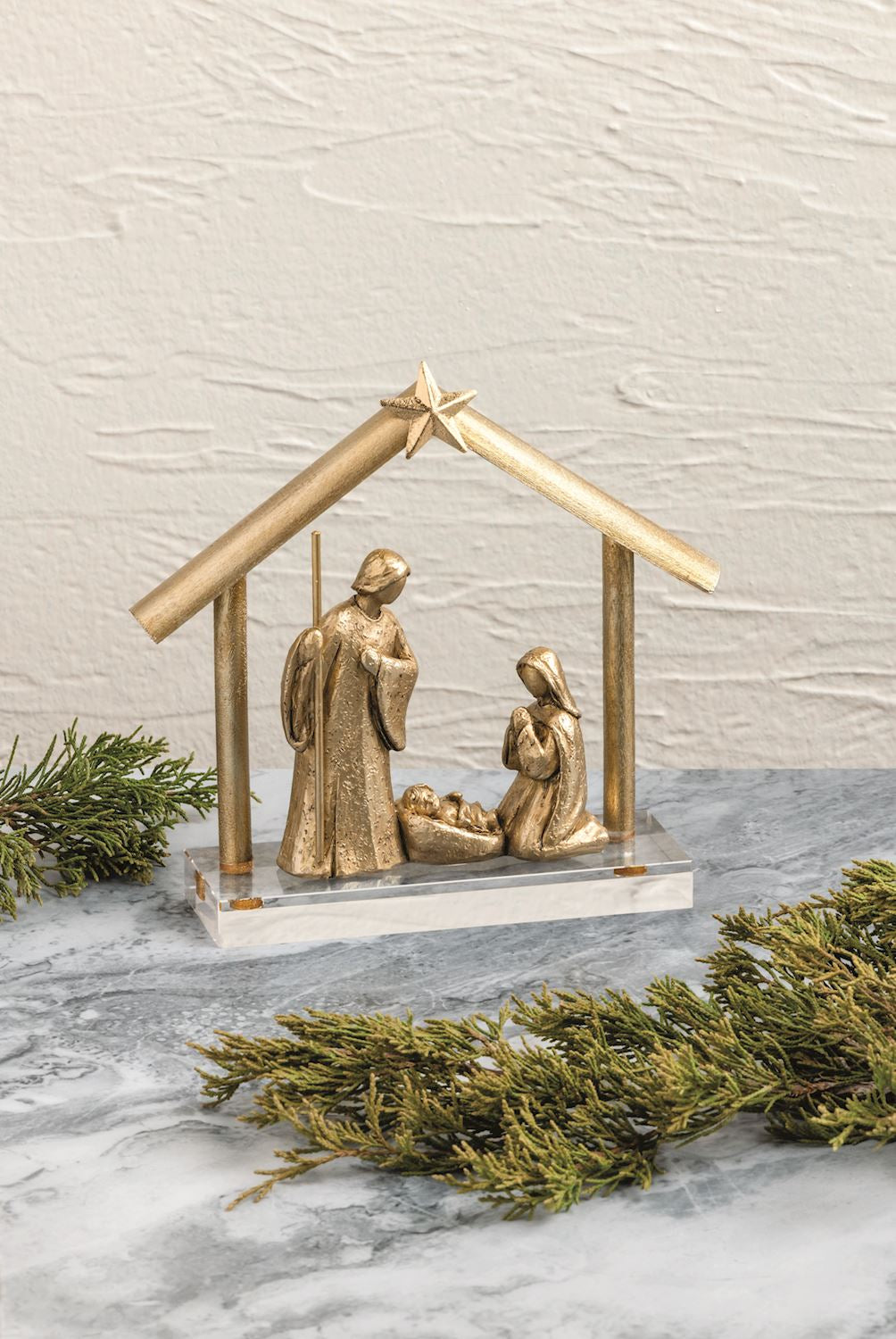 Gold Nativity display styled with holiday greenery