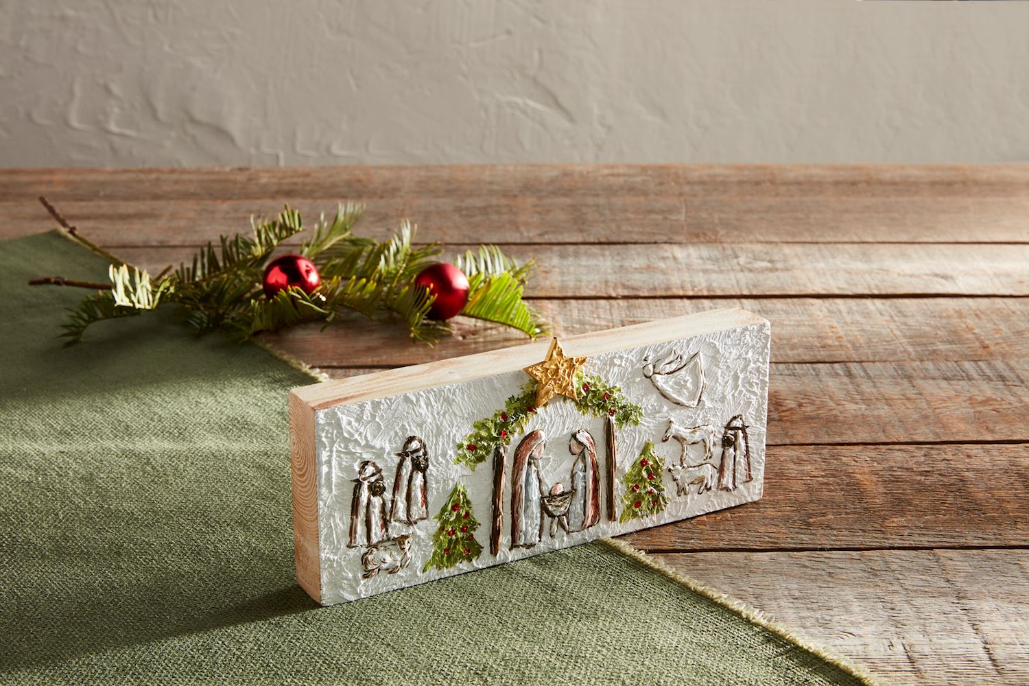 Nativity plaque displayed with holiday greenery