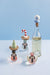 Three nutcracker wine glass and stopper sets on a light blue background