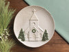 Pressed lace church platter on a table with greenery
