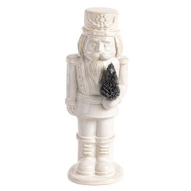 White ceramic nutcracker holding a small bottle brush tree