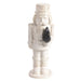 White ceramic nutcracker holding a small bottle brush tree