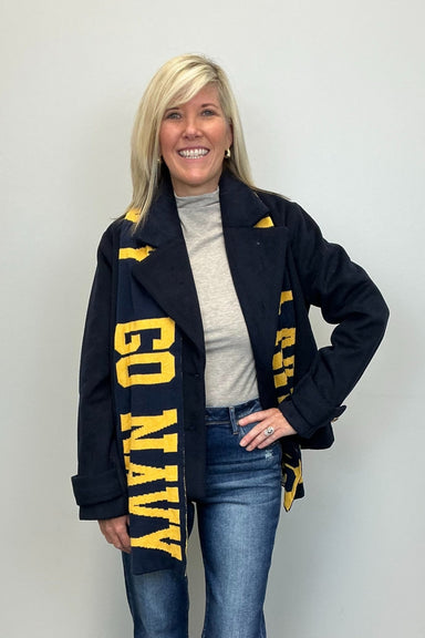 Woman wearing a navy scarf with 'GO NAVY' text, standing against a plain background