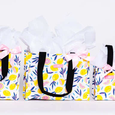 Set of three tote bags with lemon pattern and pink bows on a white background