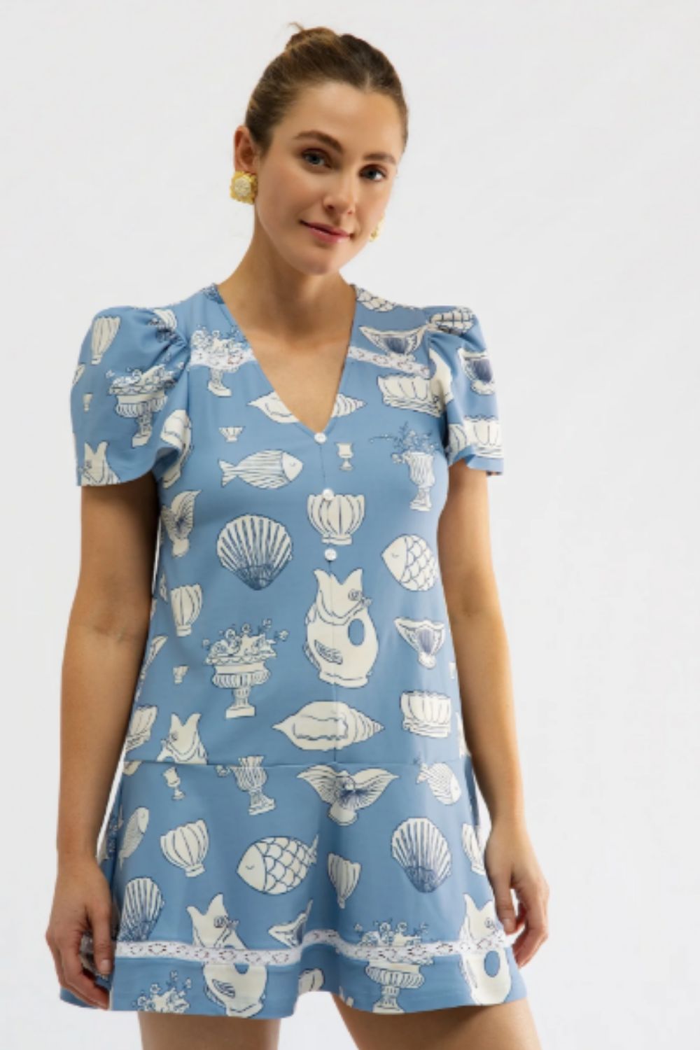 Woman wearing a blue dress with white patterns on a plain background