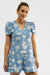 Woman wearing a blue dress with white patterns on a plain background