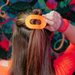 orange hair clip in models hair against colorful background
