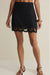 Black skirt with lace details worn by a person on a beige background