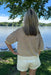 Person wearing a patterned sweater and white shorts standing by a lake