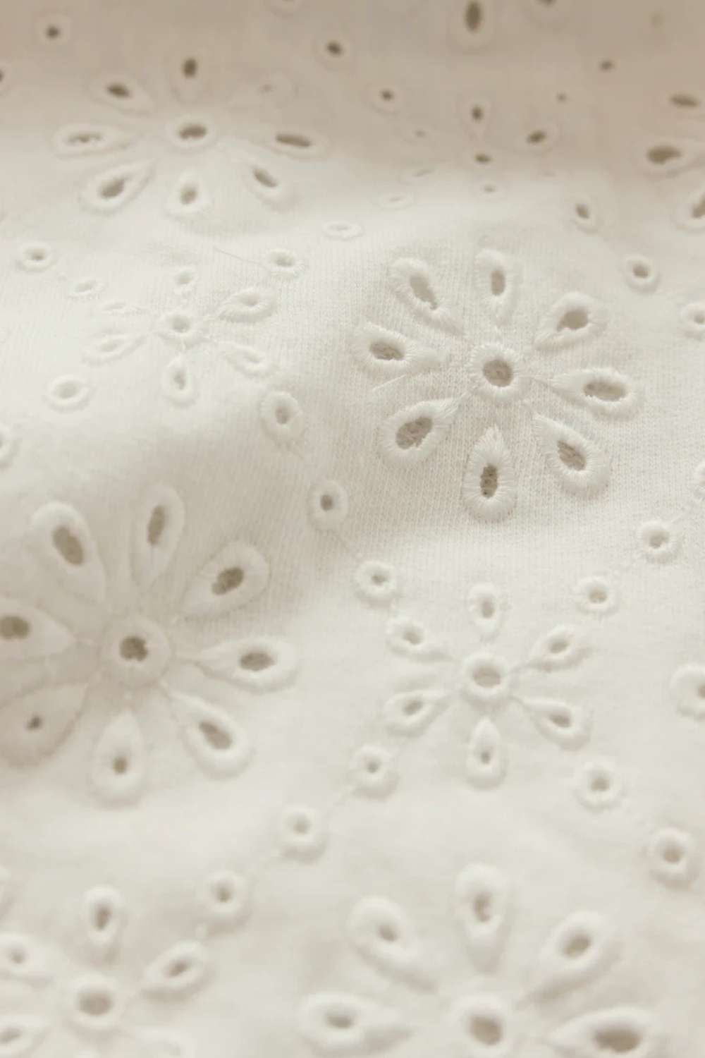 Close-up of a textured white fabric with floral cut-out pattern