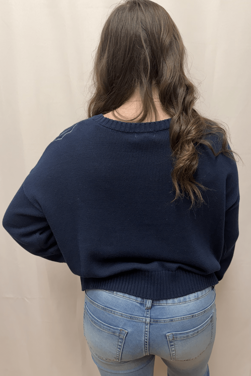 Ava wearing navy sweater with white embroidered seashells and starfish